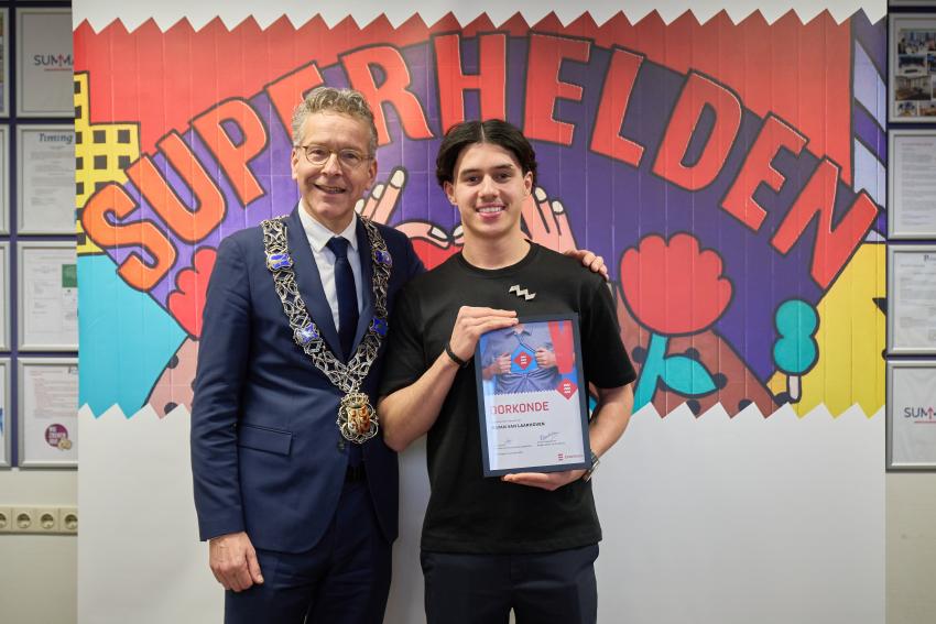 Rayan van Laarhoven met oorkonde en jeugdlintje samen met burgemeester Dijsselbloem