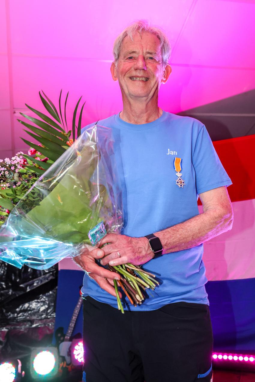 Jan van Diepen met zijn opgespelde koninklijke onderscheiding en een bos bloemen