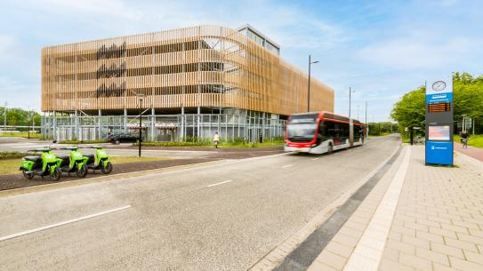 Gebouw P en R Genneper Parken met rijdende bus ernaast, klik voor een vergroting