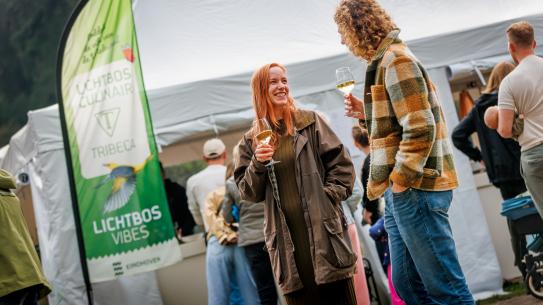 Bezoekers doen een hapje en een drankje van restaurant Tribeca tijdens Lichtbos Culinair, klik voor een vergroting