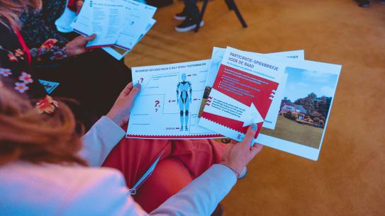 Bezoekers bekijken flyers over participatie, klik voor een vergroting