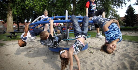 kinderen die met hun benen aan een speelrek hangen