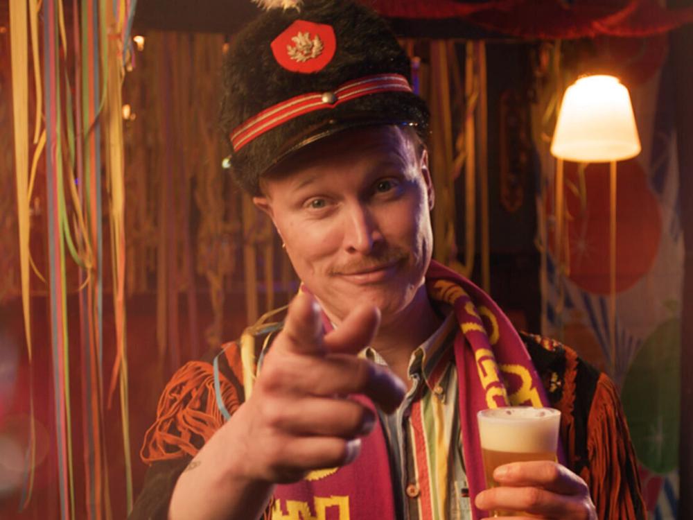 Beeld van een man in carnavalspak naast de slogan 'houd je cup erbij'