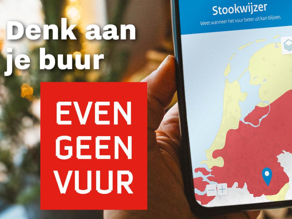 Afbeelding van een smartphone met daarop de pagina Stookwijzer.nu geopend. Ernaast staat de tekst ''Denk aan je buur, even geen vuur'', en de website www.stookwijzer.nu.