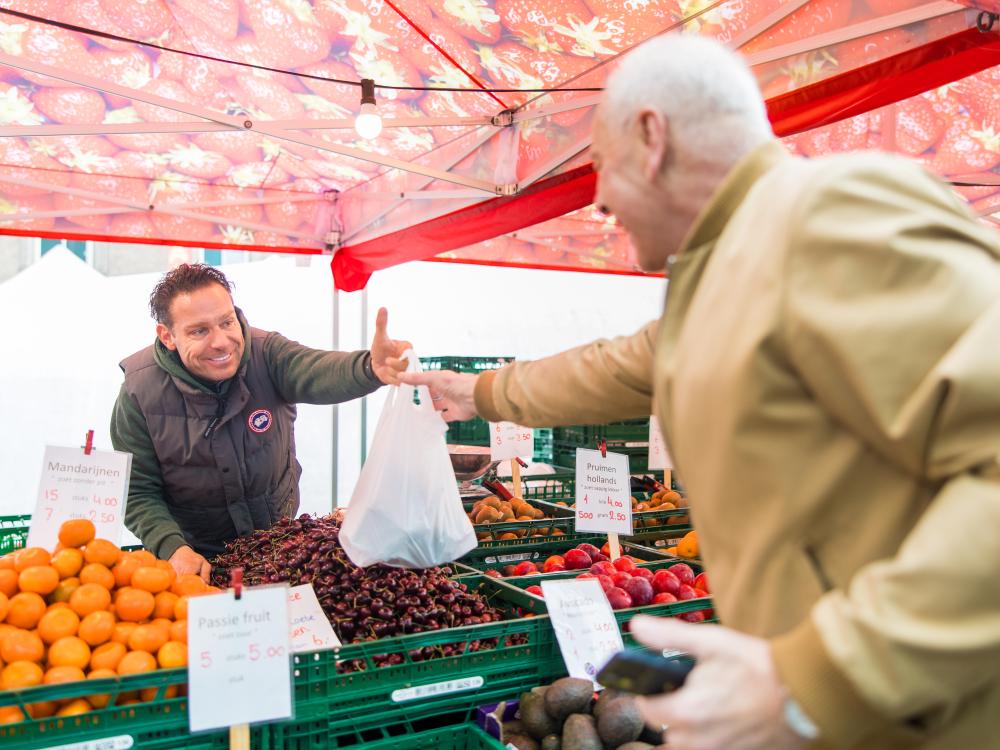 Op deze afbeelding staan twee personen op de weekmarkt.
